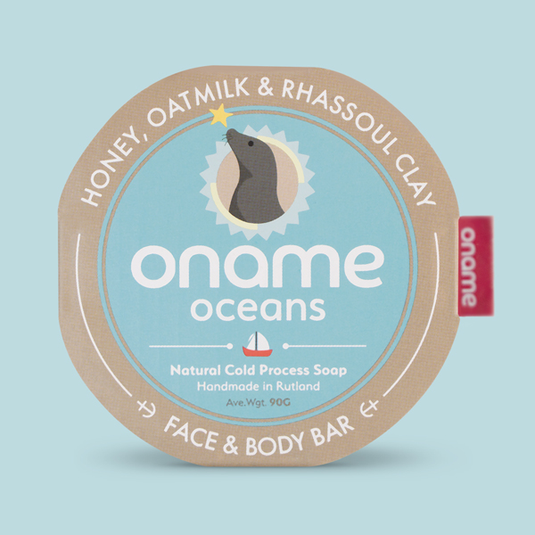 Oname Honey, Oatmilk & Rhassoul Clay soap on a blue background