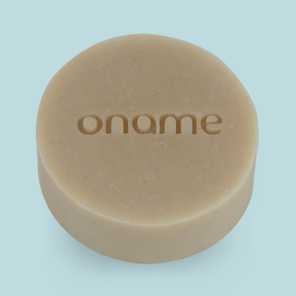 Oname Honey, Oatmilk & Rhassoul Clay soap on a blue background
